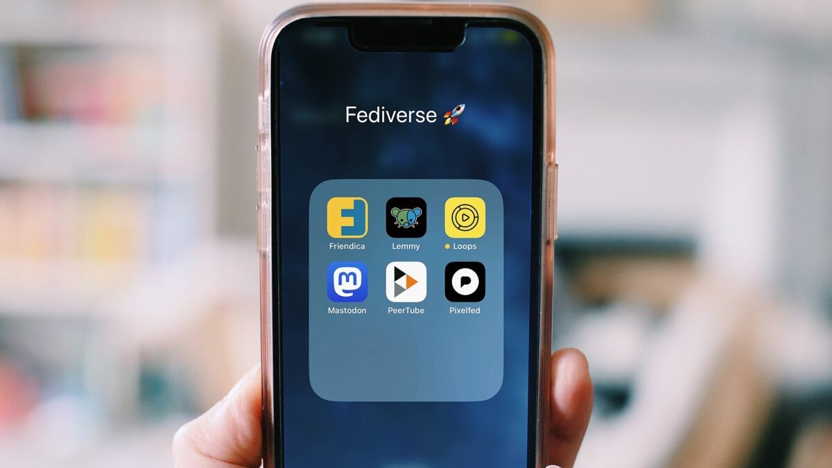 Main tenant un smartphone affichant un dossier d'applications