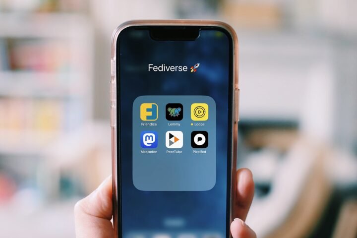 Main tenant un smartphone affichant un dossier d'applications