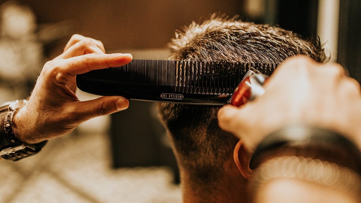 Coiffeur coupant les cheveux d'un homme au peigne et aux ciseaux
