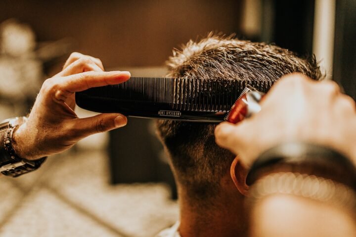 Coiffeur coupant les cheveux d'un homme au peigne et aux ciseaux
