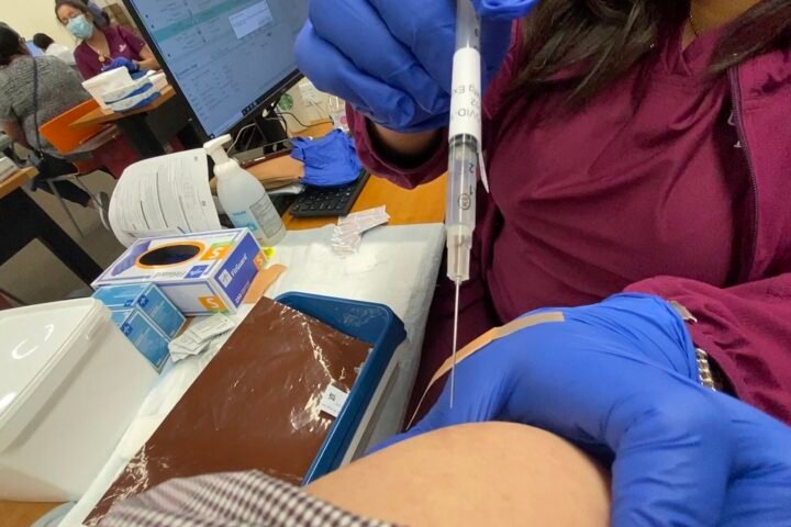 Injection d'un vaccin dans le bras d'une personne, dans un centre de vaccination
